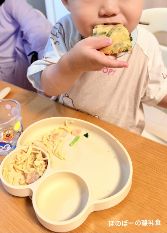 野菜入りのおやきを手づかみで食べる1歳10か月の息子
